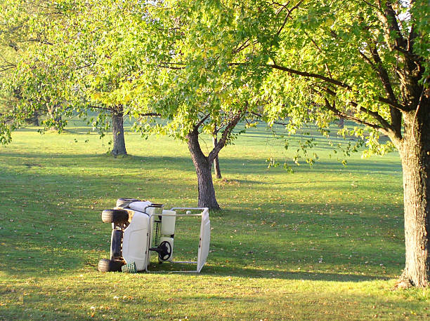 Wrecked golfcart abandoned and flipped on its side lying on the golf course.